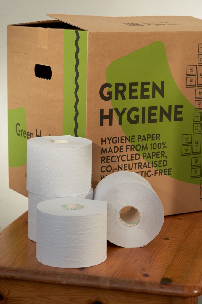 Wie nutzen nachhaltiges Hygienepapier in unserer Praxis für Physiotherapie: Das vollständig recycelte Toilettenpapier steht vor dem plastikfreien Verpackungskarton.